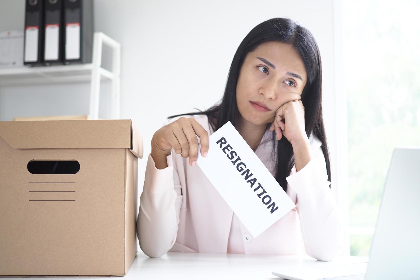 A young businesswoman is bored and thinks of sending a resignation letter. photo