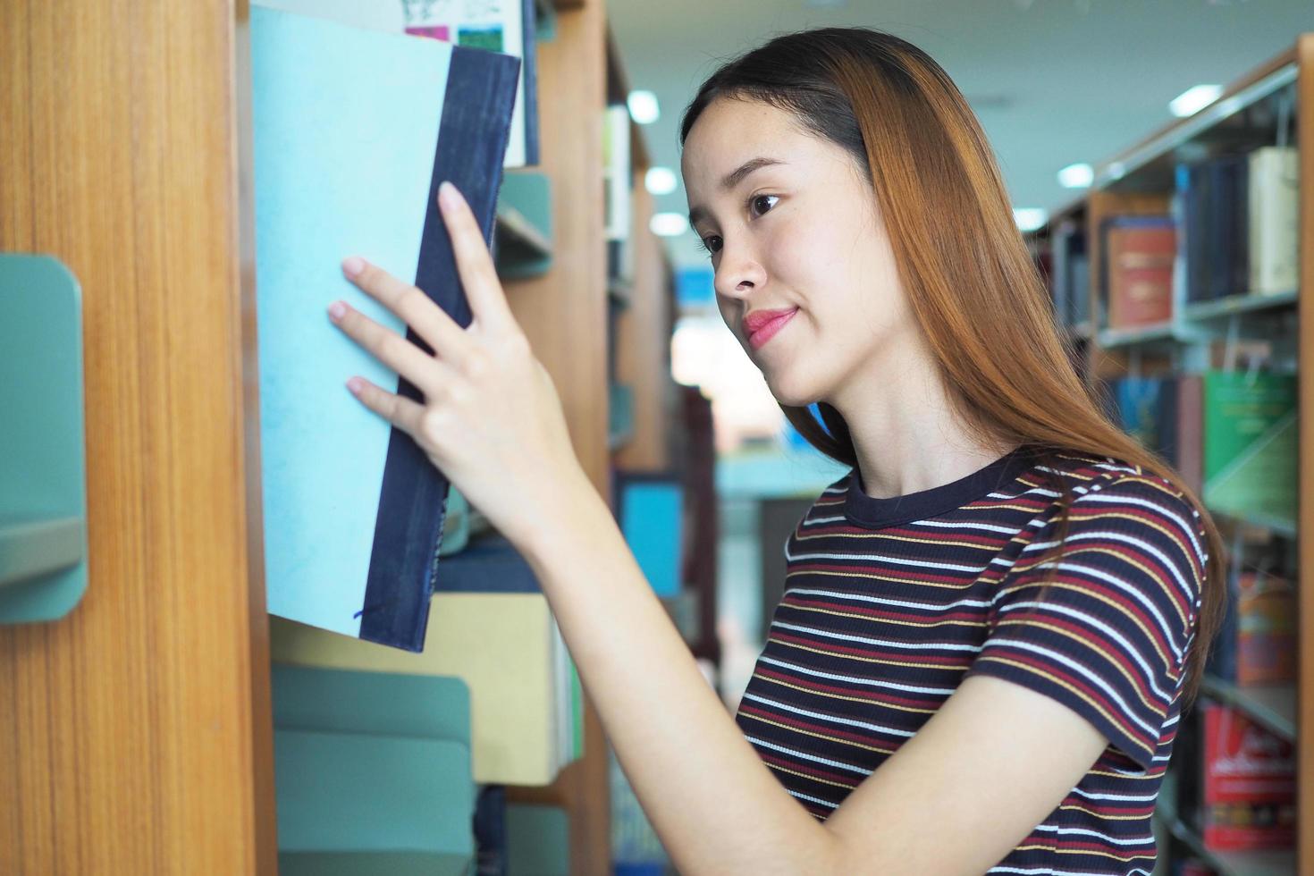 los estudiantes de secundaria o universitarios eligen libros en los estantes de la biblioteca. foto