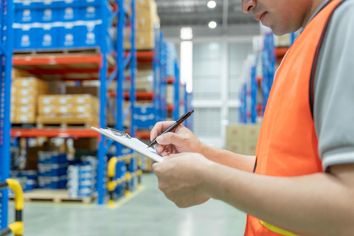 asian man business owner using checklist recheck amount of stock product inventory on shelf at distribution warehouse factory.logistic business ship and delivery, inventory flow, professional. photo