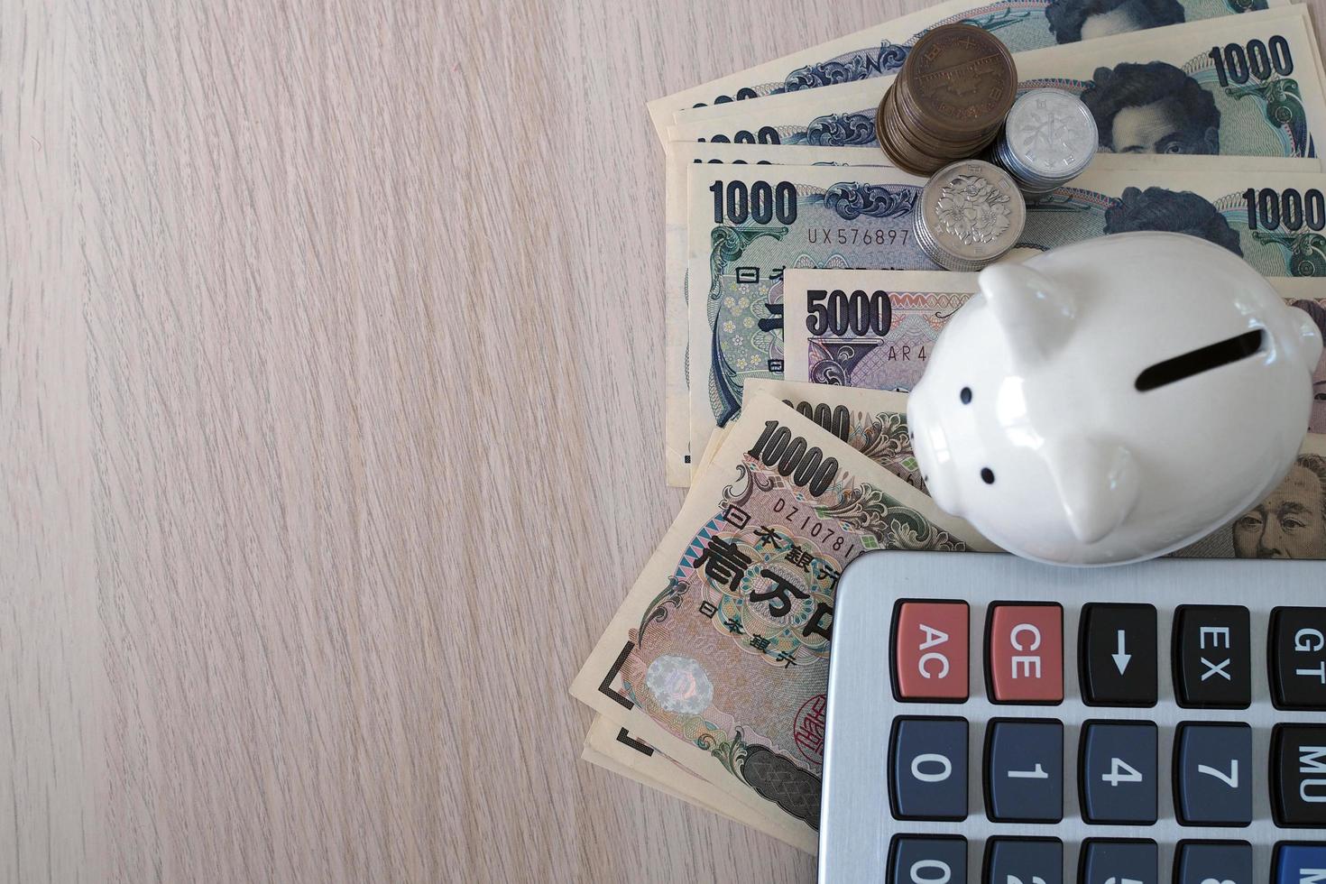 Piggy bank and calculator Placed with Japanese Yen banknotes and Japanese Yen coins for money concept background photo