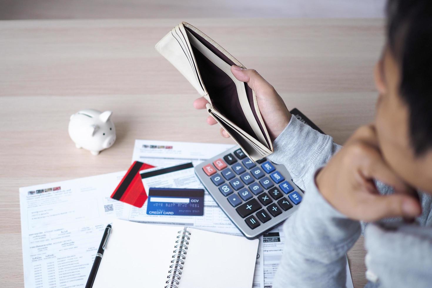 Picture of Asian man with financial concerns carrying an empty purse. Thinking hard about paying off credit card debt, home rentals and family expenses. Financial problem and debt concept photo