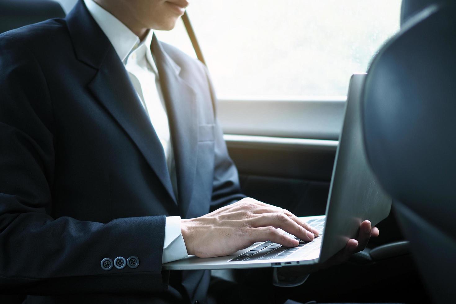 los ejecutivos usan computadoras portátiles para trabajar mientras viajan y se sientan dentro del automóvil. foto