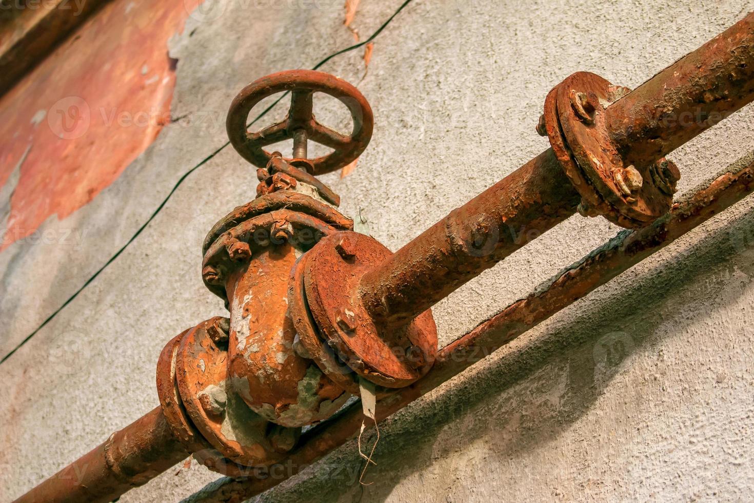 Rusty old gas tap on the background of the wall of the house. photo