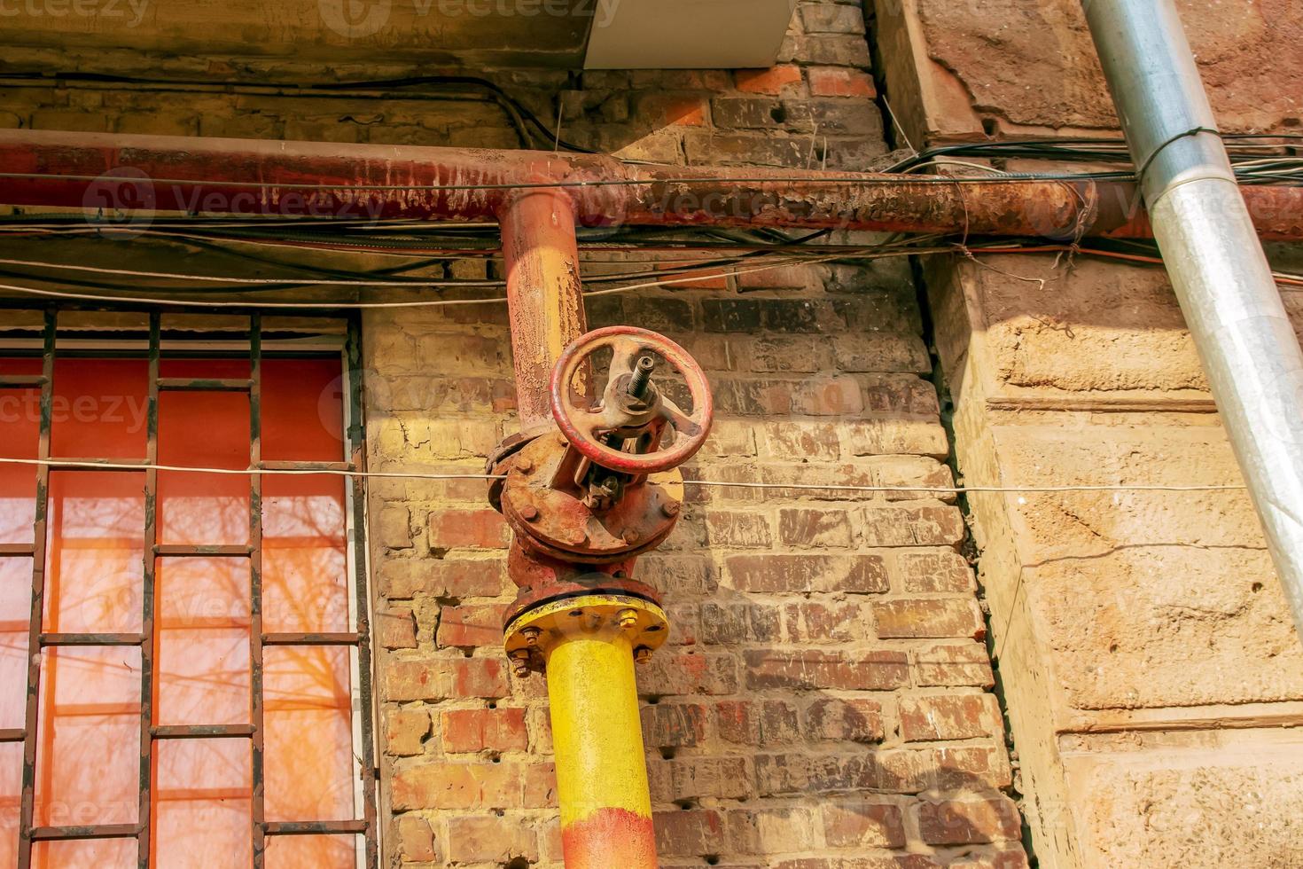 Rusty old gas tap on the background of the wall of the house. photo