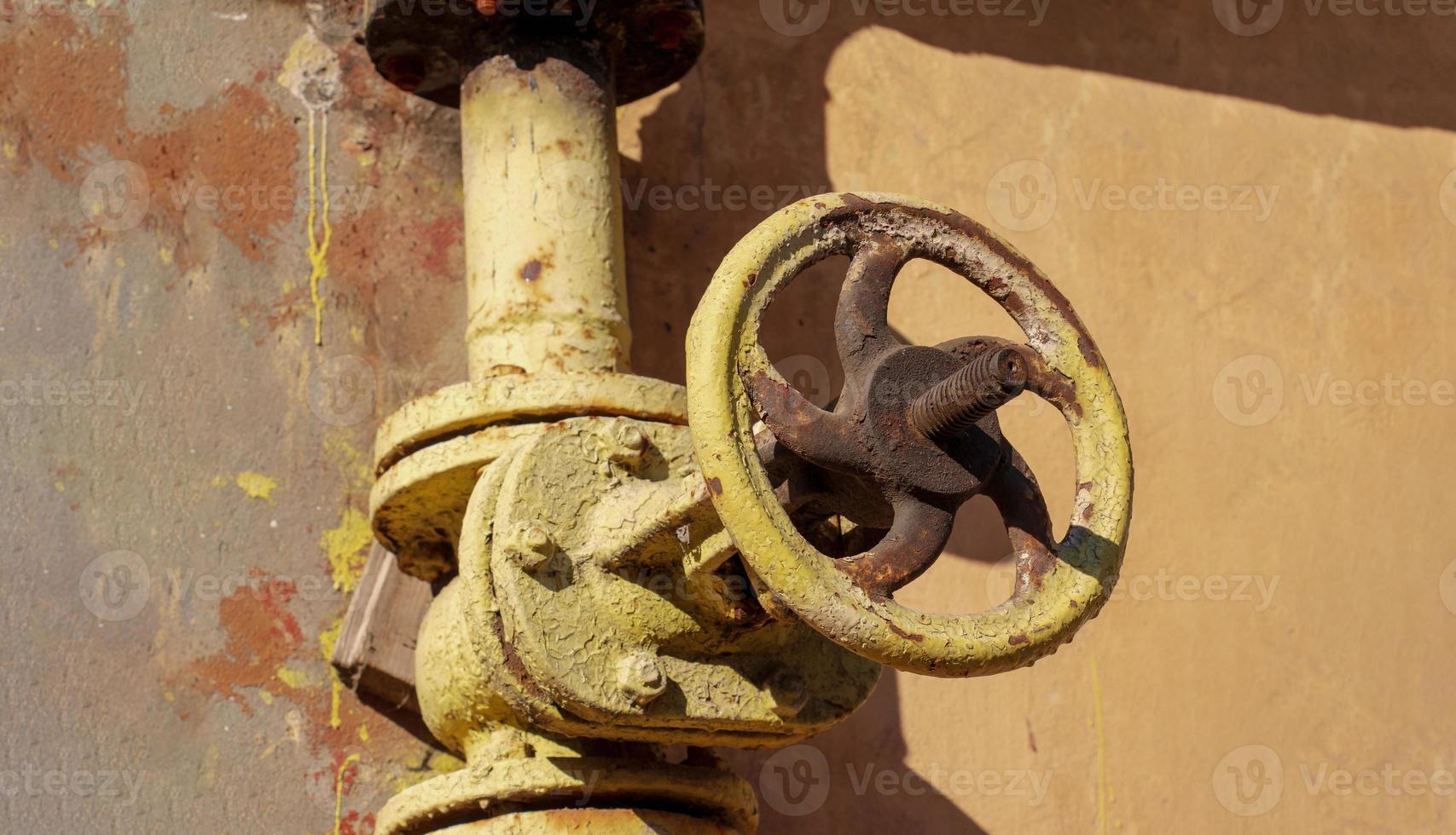 Rusty old gas tap on the background of the wall of the house. photo