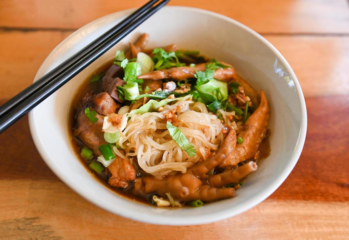 chicken noodles with chicken feet and chicken wings and vegetable on soup bowl , Thai food stewed with chinese herbs photo