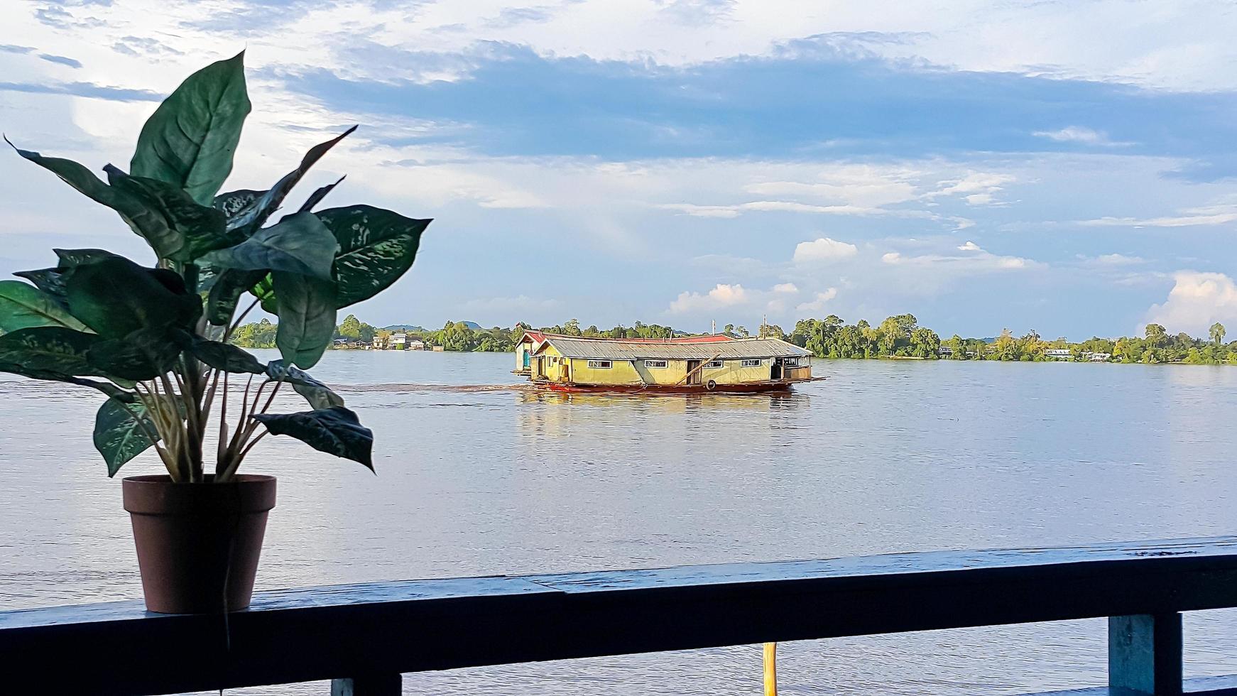 Bandong ship or Kapal Bandong on the Kapuas river, West Kalimantan. View from the Kapuas riverside with a plant in the pot. Clear blue sky. photo