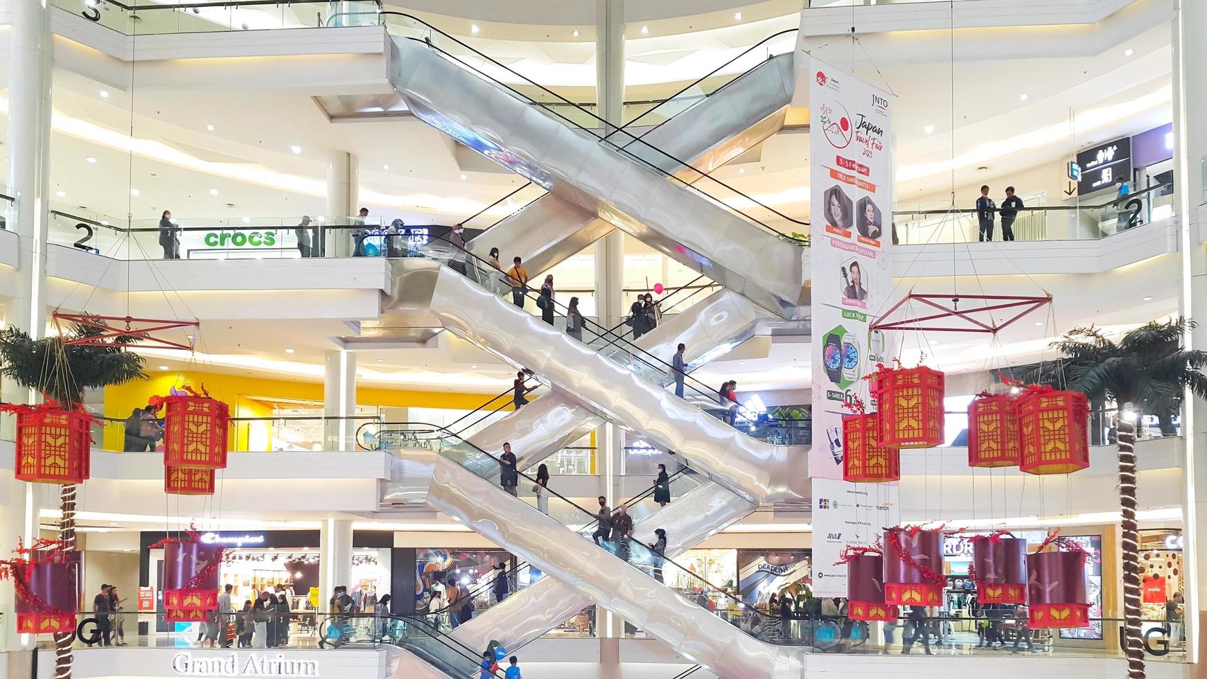Jakarta, Indonesia, February 04, 2023 - Side view of several criss-cross positioned escalators with crowds of people in Kota Kasablanka Shopping Mall photo