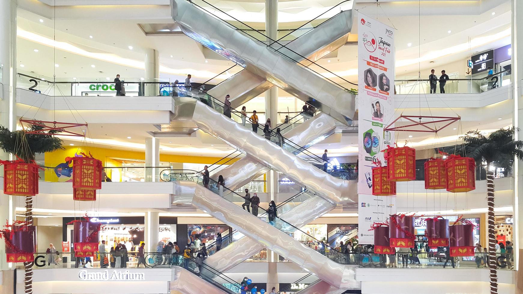 Jakarta, Indonesia, February 04, 2023 - Side view of several criss-cross positioned escalators with crowds of people in Kota Kasablanka Shopping Mall photo