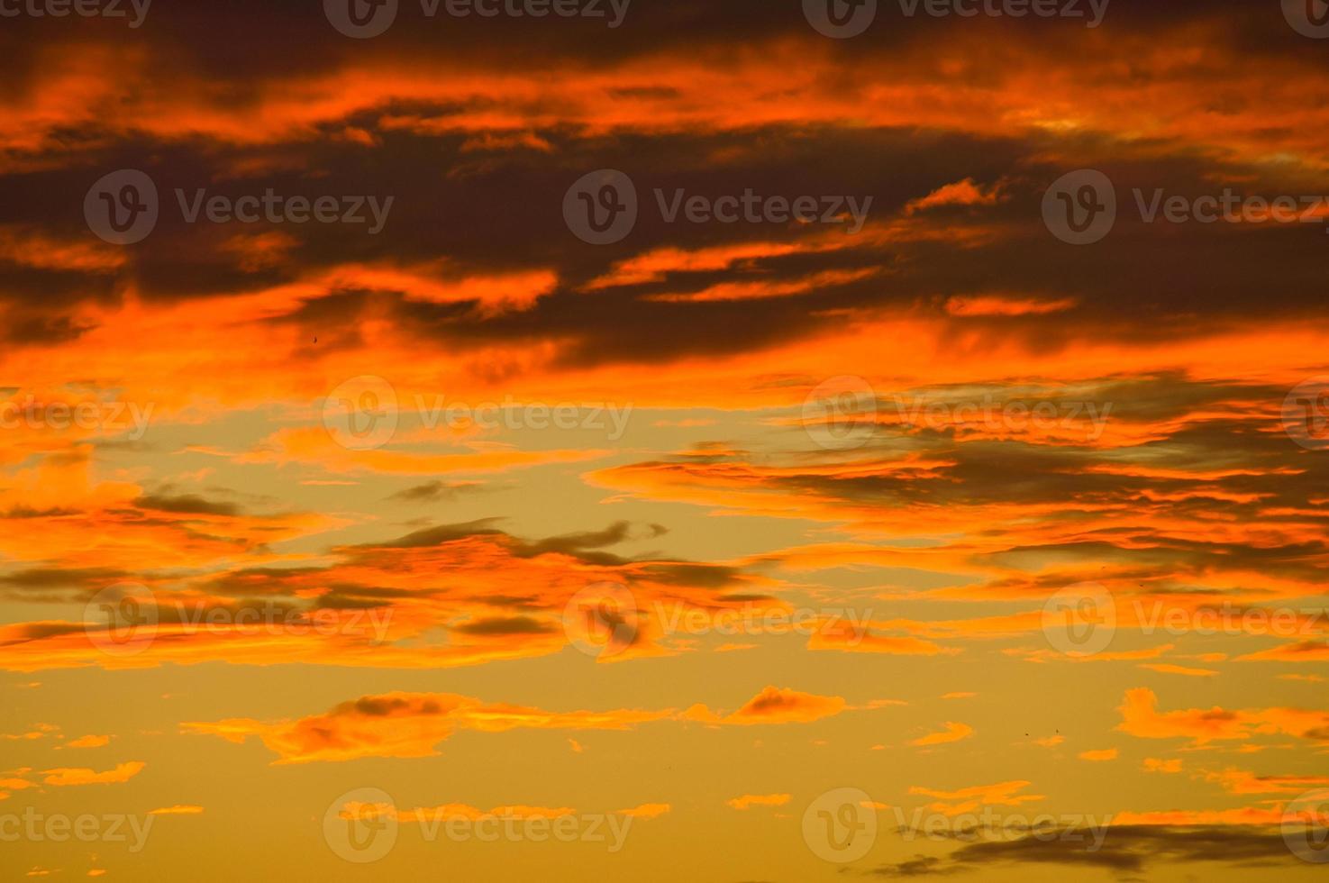 Background image with clouds in extreme colors of a sunset. The sky seems to burn photo