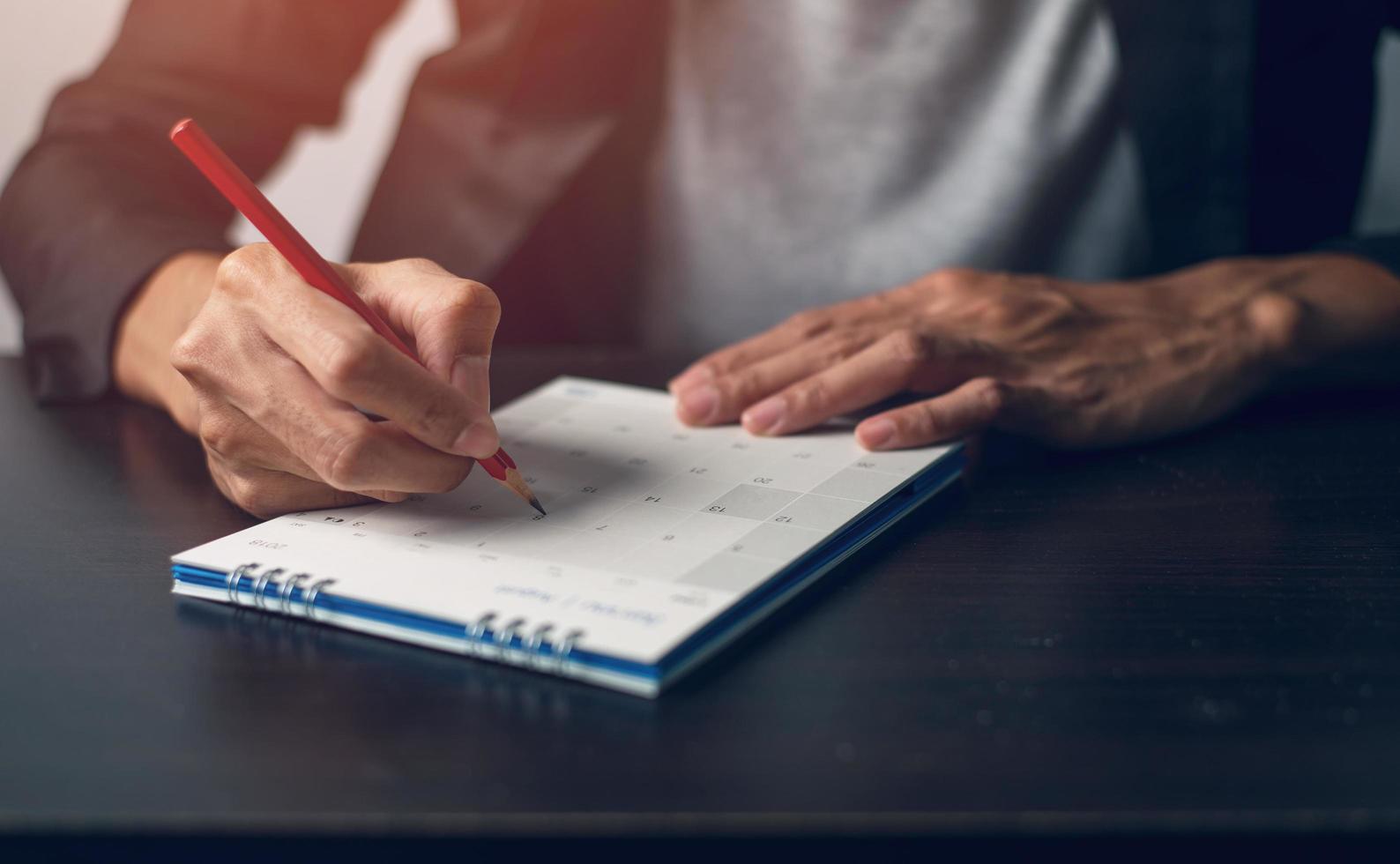 la mano del hombre es escribir una nota en un calendario foto