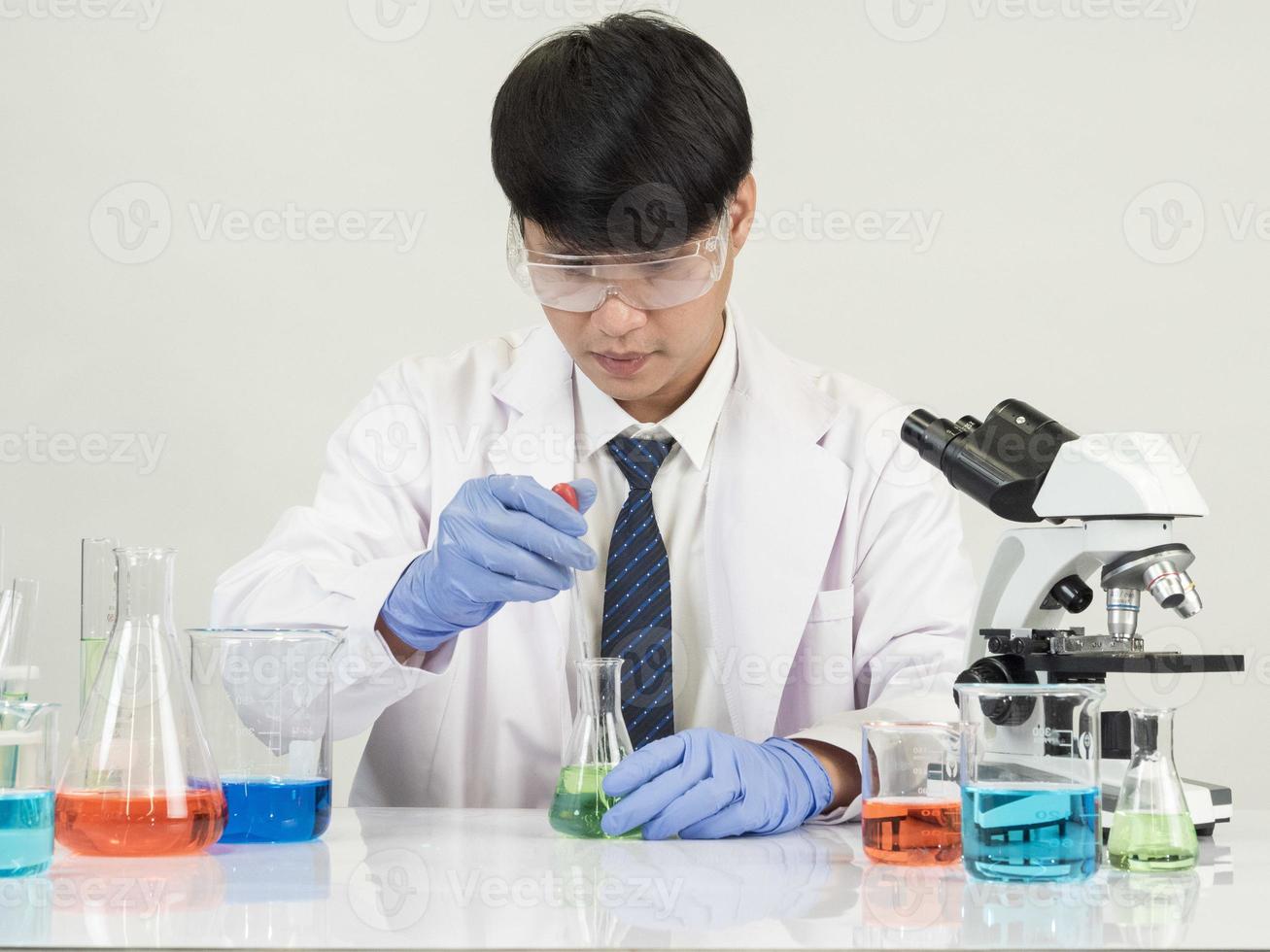 Asian male student scientist in reagent mixing laboratory In a science research laboratory with test tubes of various sizes and microscopes. on the table in  laboratory chemistry lab white background. photo