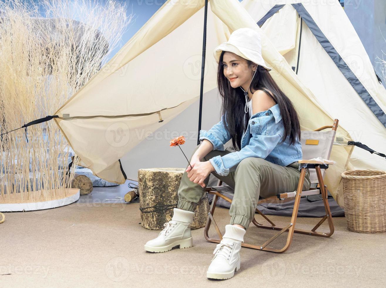 Portrait beautiful young girl woman Asian pretty smile wearing a hat jacket blue one person alone sitting on a chair camping travel trip in front of  tent, on freedom relax happy enjoy in vacation. photo