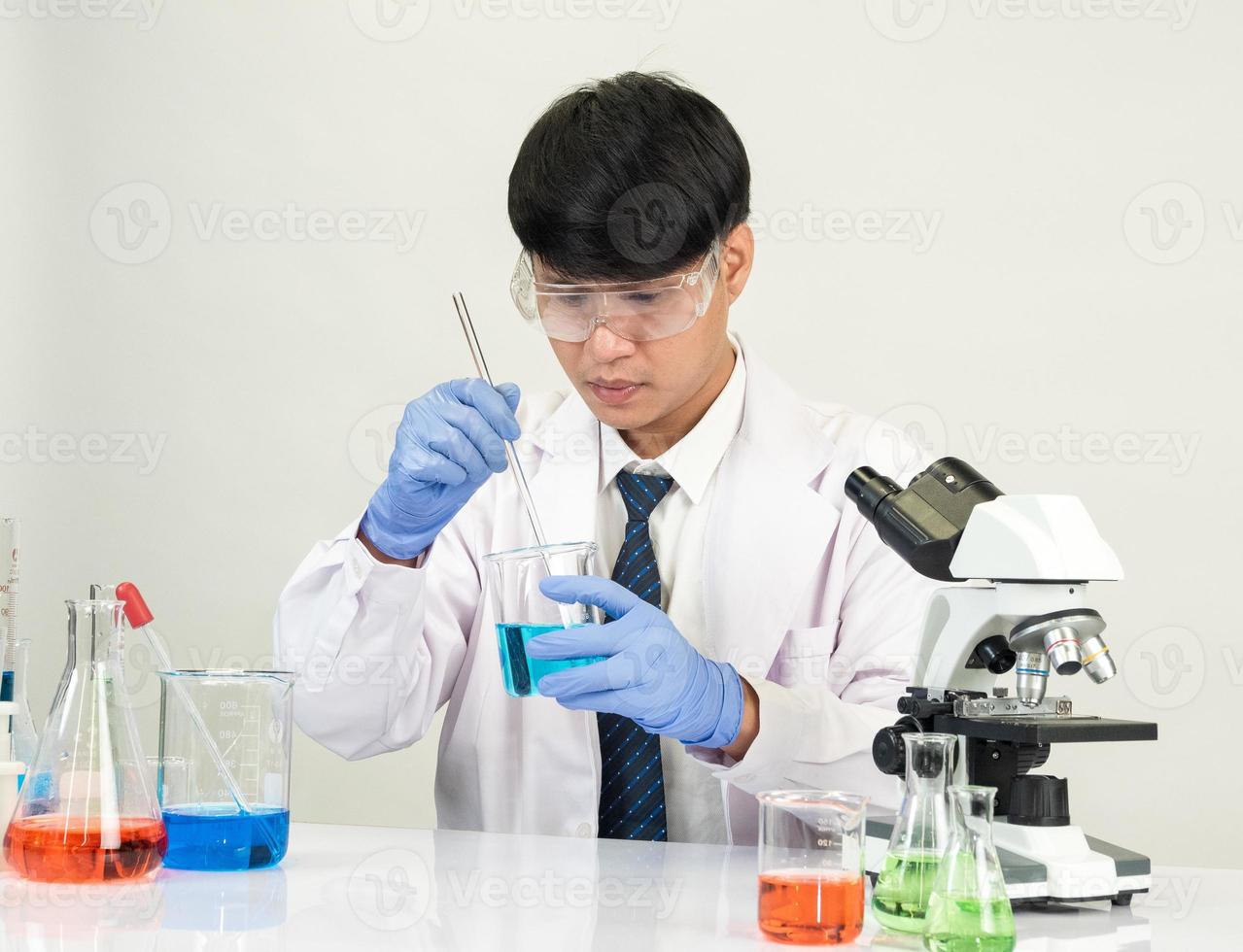 Asian male student scientist in reagent mixing laboratory In a science research laboratory with test tubes of various sizes and microscopes. on the table in  laboratory chemistry lab white background. photo