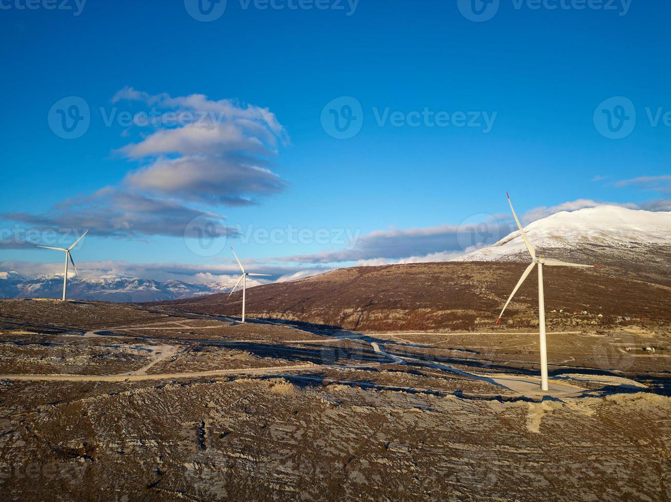 Windmills on the hills during sunset. Renewable energy, green energy. Mountains in the background with snow. Wind power and environmentally friendly. Sustainable future. End fossil fuels. photo