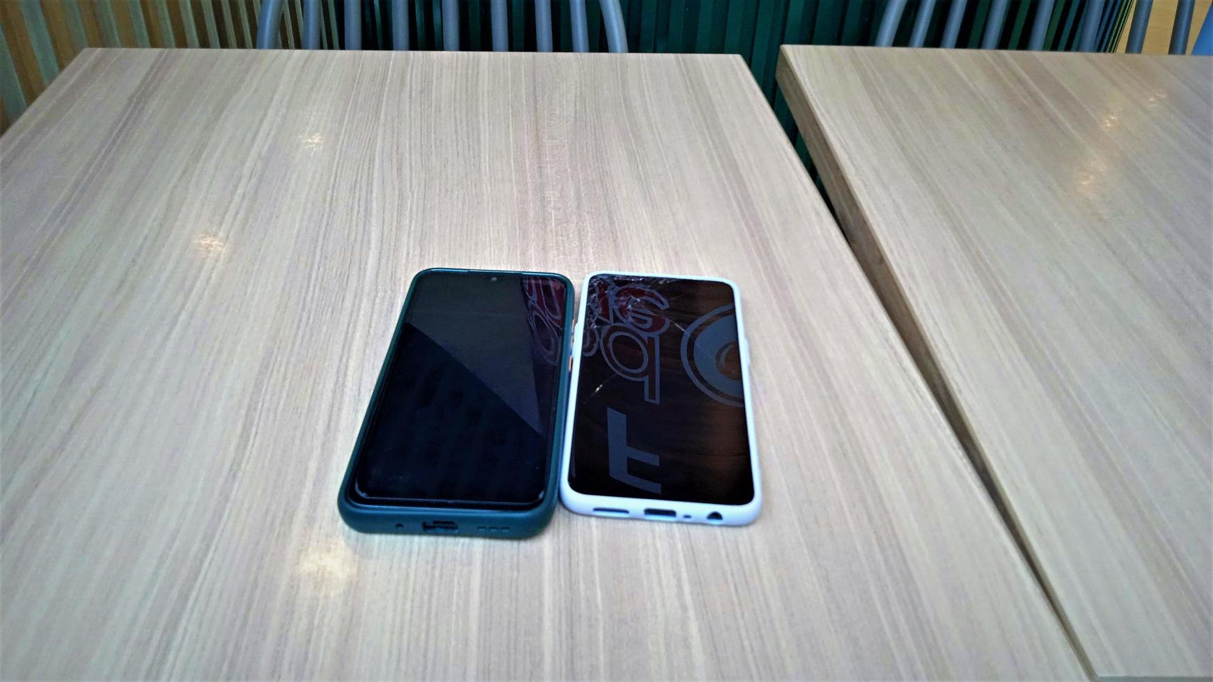 Two cell phones on a wooden table. photo