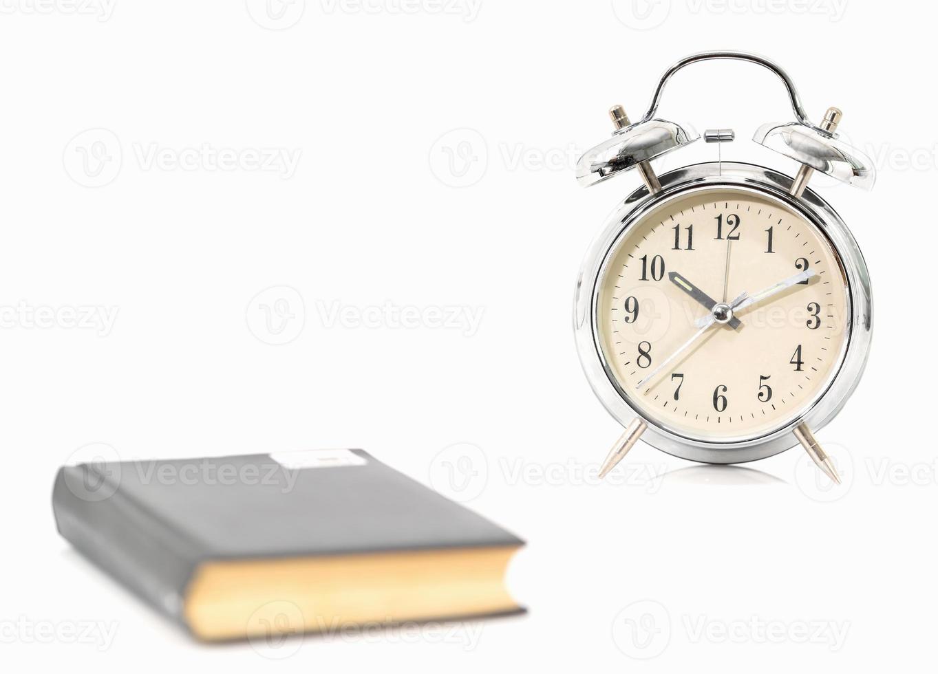 Silver alarm clock and old book photo
