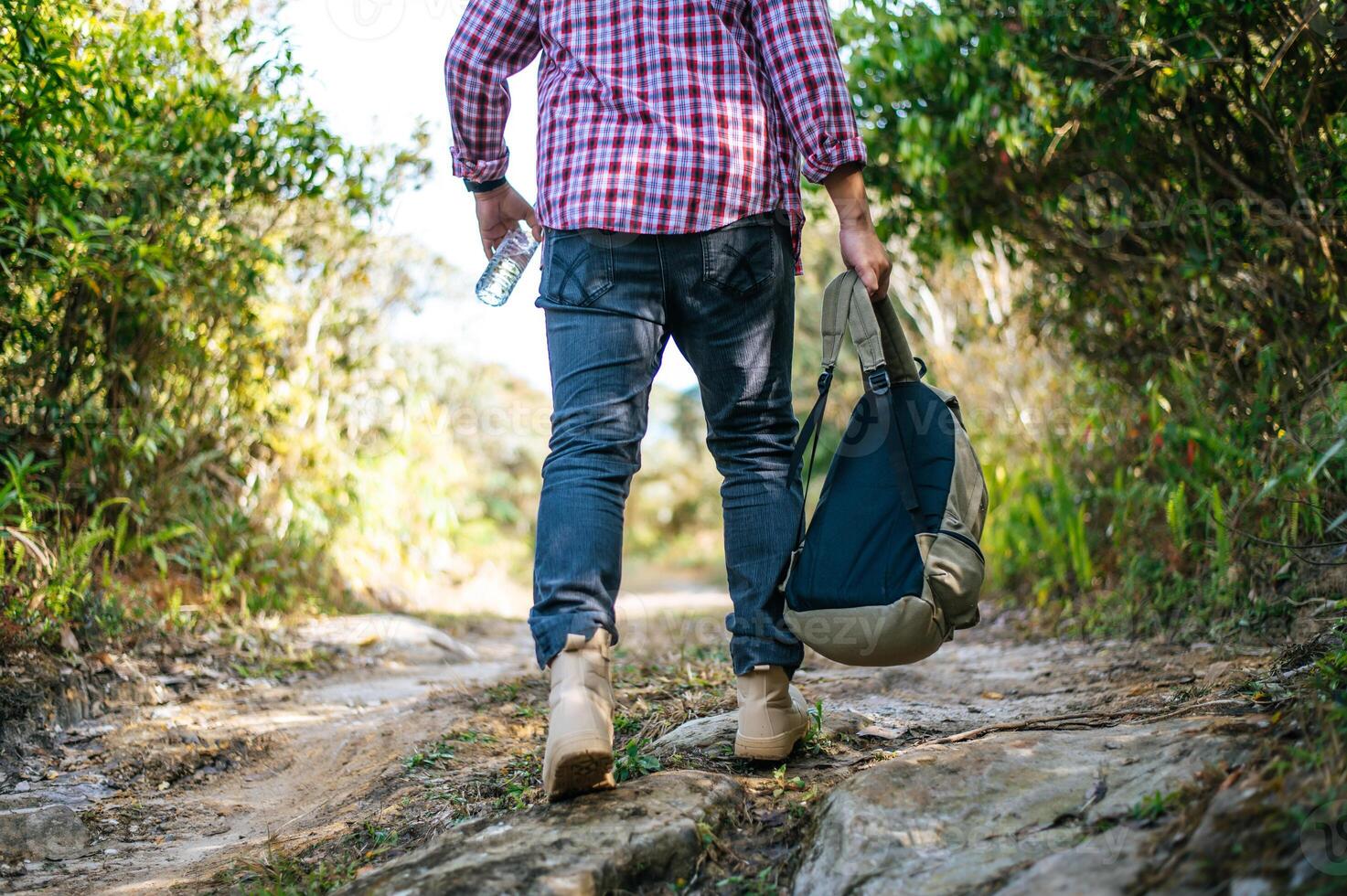 Young trekking man walking on trail in forest with backpack photo