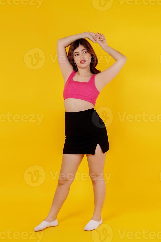 Full length portrait of a beautiful young woman posing isolated over yellow background photo