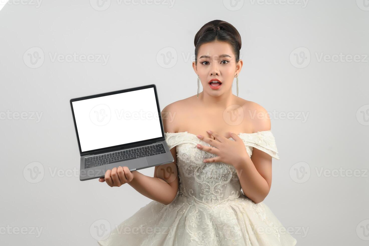 Una joven novia asiática hermosa posa con una computadora portátil de maqueta en la mano foto