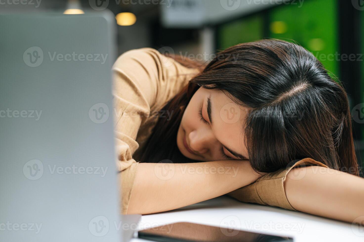 Young woman asleep on table after working on laptop computer photo