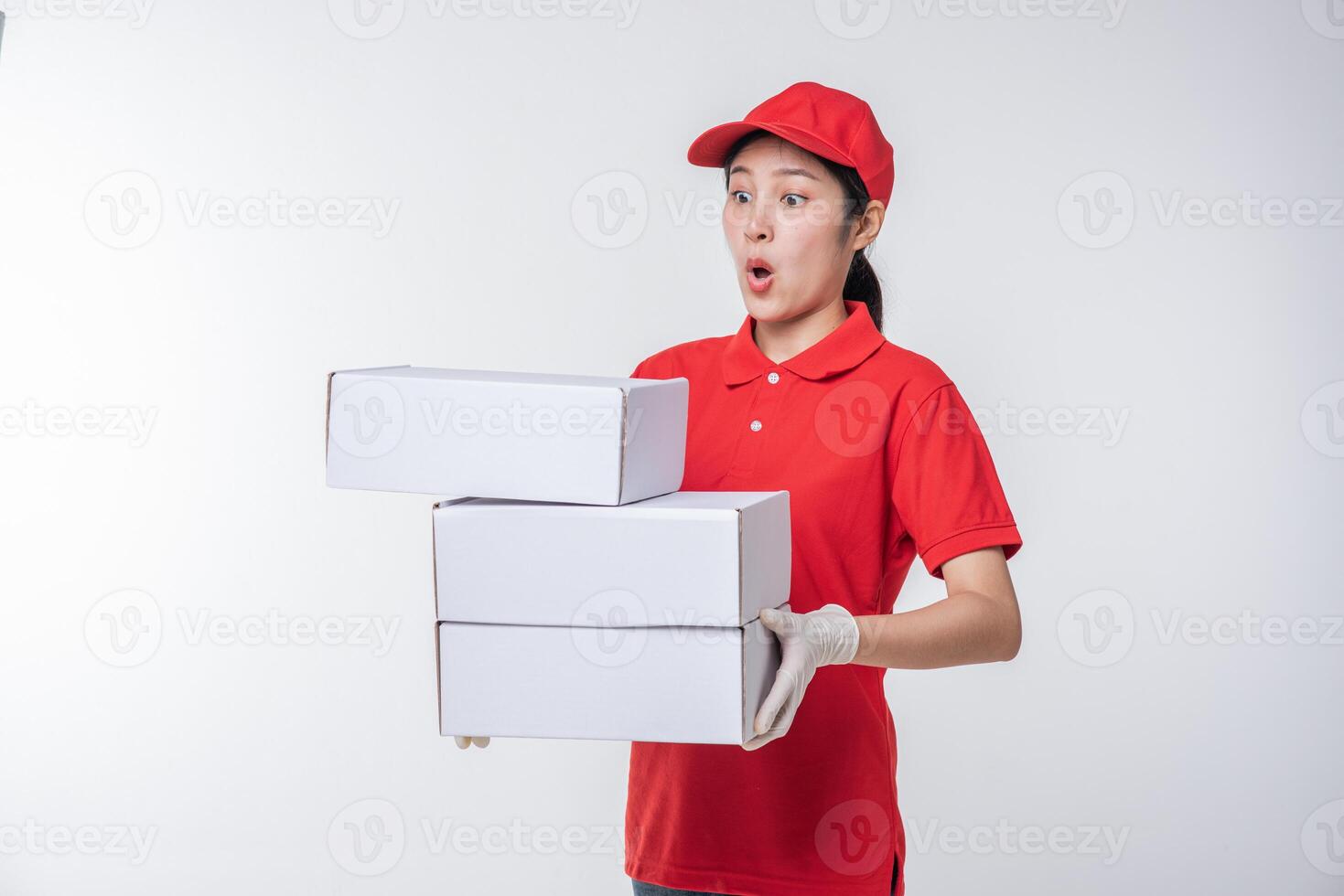 Image of  young delivery man in red cap blank t-shirt uniform standing with empty white cardboard box isolated on light gray background studio photo