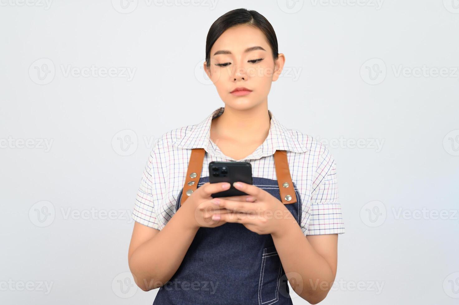 Portrait of young asian woman in waitress uniform pose with smartphone photo