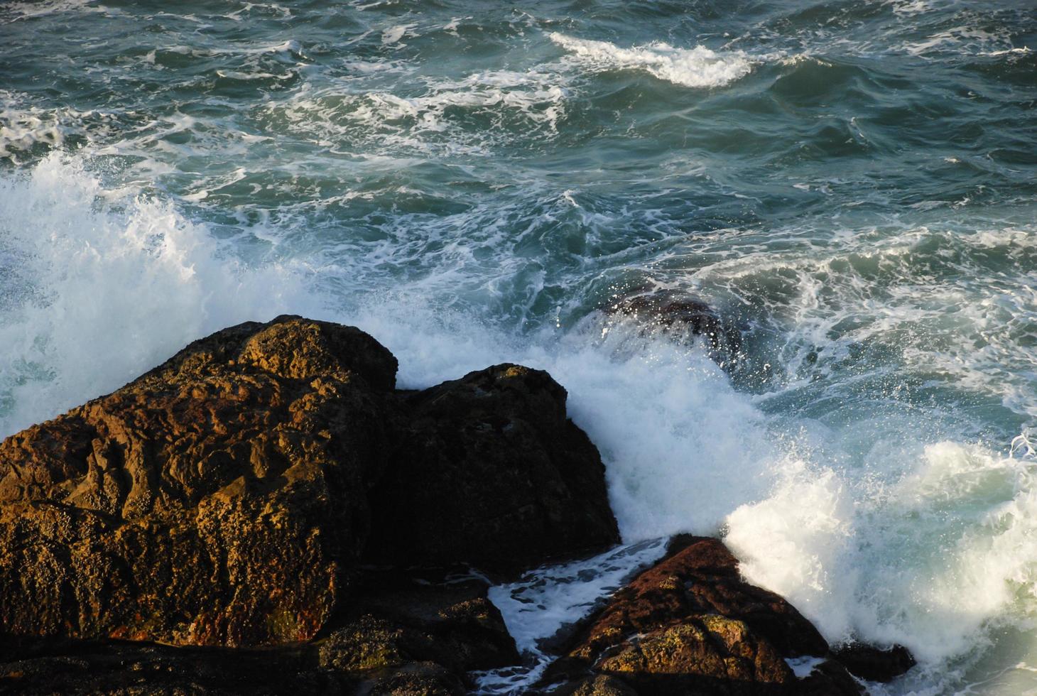 Waves hitting rocks at sunset photo