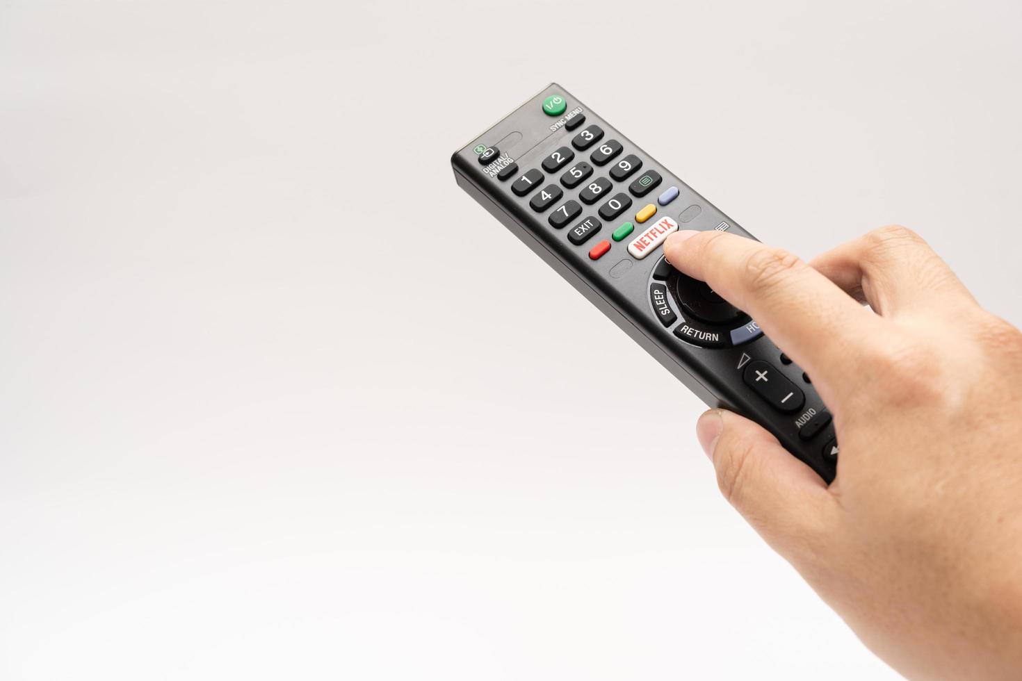 Samutprakarn Thailand Jan 23 2023 A Smart TV remote commander with Smart TV Assistant function like Netflix. Male hand holding television remote Netflix. photo
