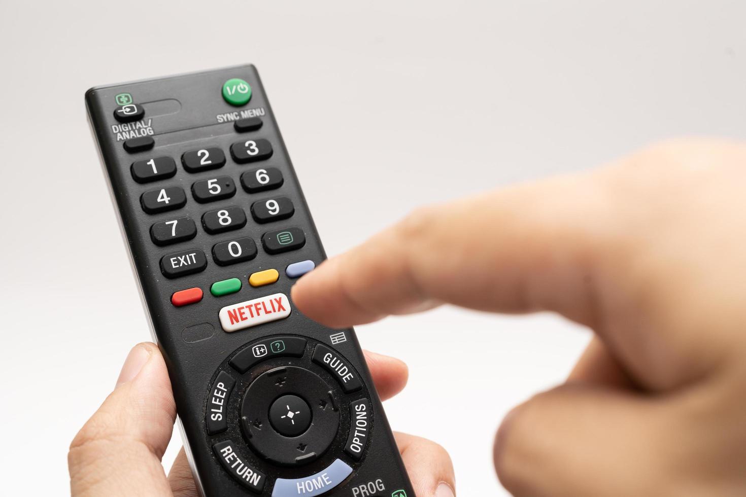 Samutprakarn Thailand Jan 23 2023 A Smart TV remote commander with Smart TV Assistant function like Netflix. Male hand holding television remote Netflix. photo