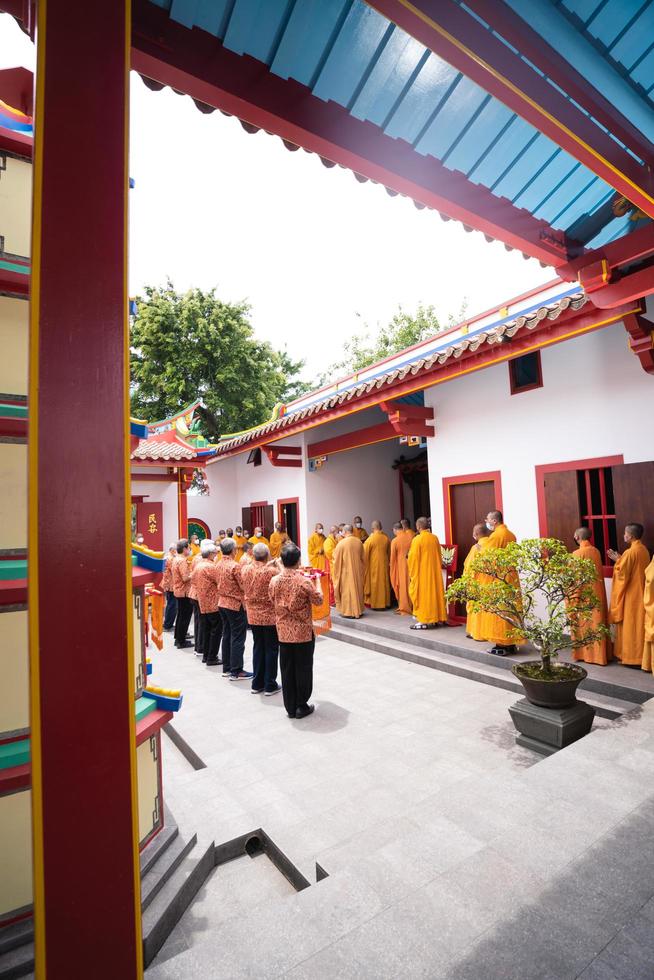 Bandung, Indonesia, 2020 - The monks in orange rob standing in order while praying to the god at the altar inside the Buddha temple photo