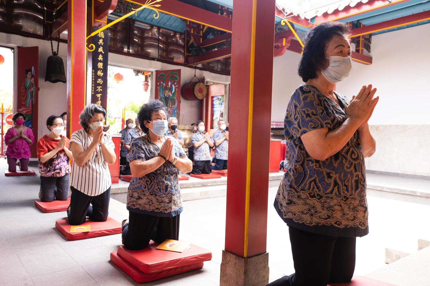 Bandung, Indonesia, 2020 - Buddhist People pray together with the monks while giving the offering in front of the altar photo