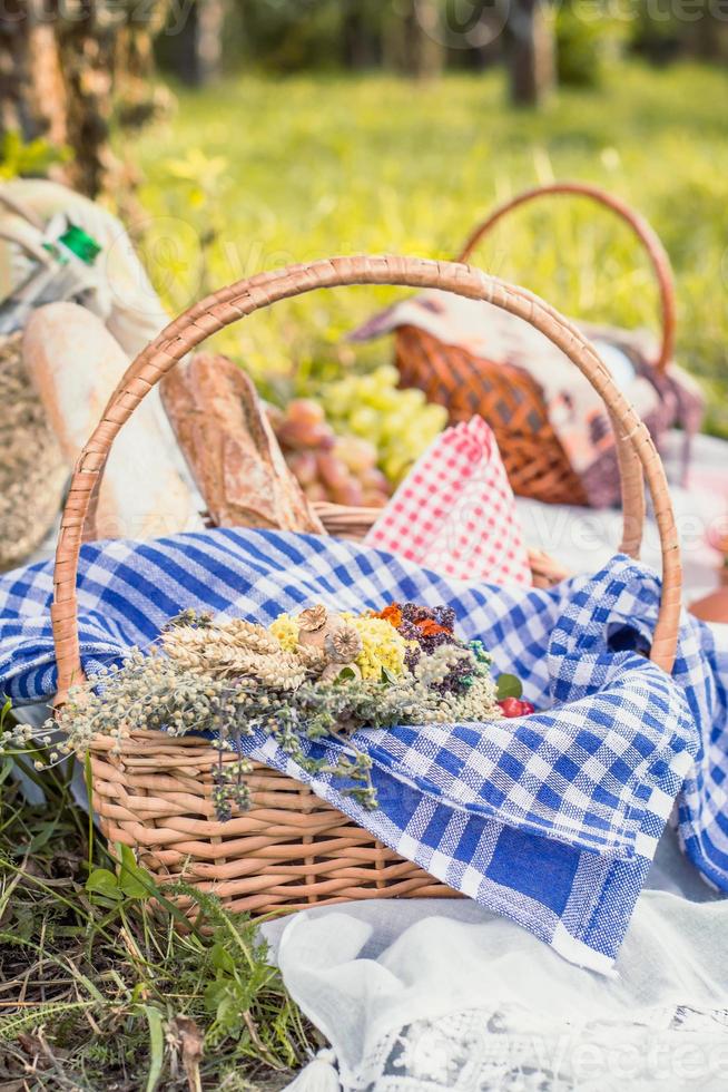 cesta tejida de cerca con flores silvestres, baguette en foto de concepto de picnic