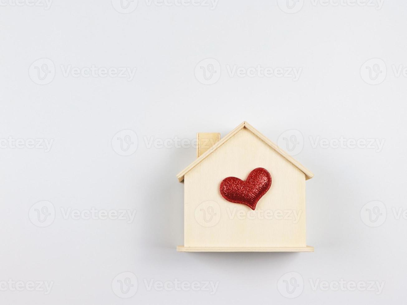 endecha plana de casa modelo de madera con corazón de brillo rojo aislado sobre fondo blanco. casa de ensueño, hogar de amor, relación fuerte, san valentín. foto