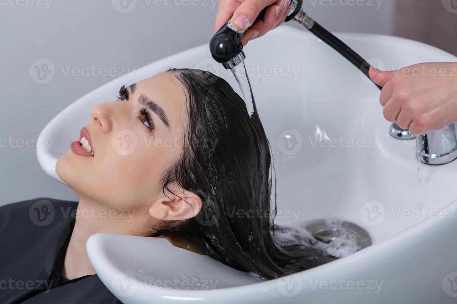 professional hairdresser washing hair of young woman in beauty salon. close up of woman's hair in beauty salon, hairstyle concept photo
