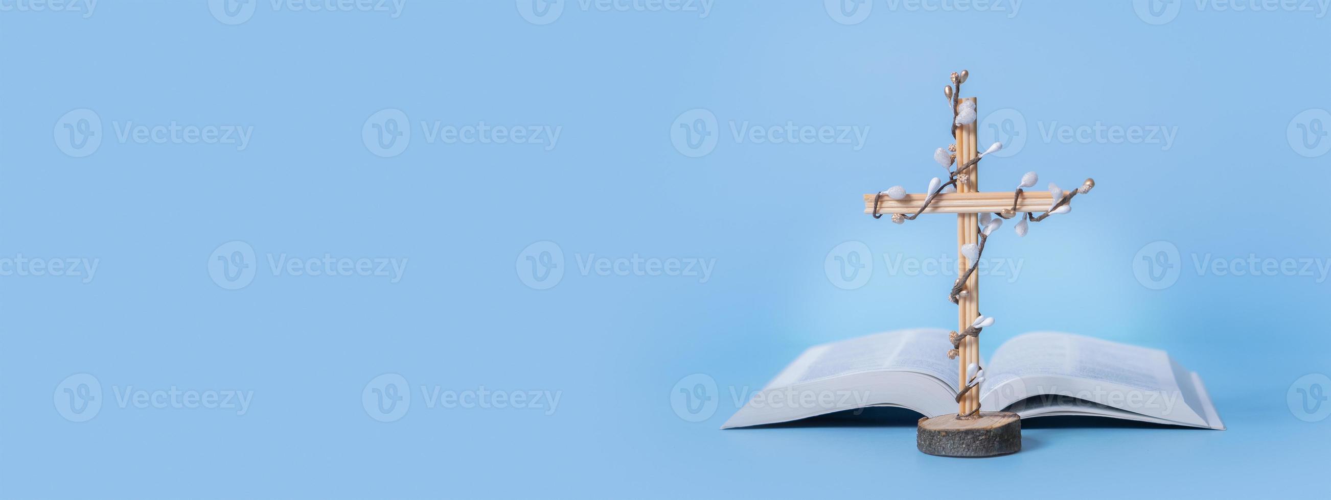 Banner with cross and Holy Bible on blue background with copy space. Easter holiday minimalistic concept photo