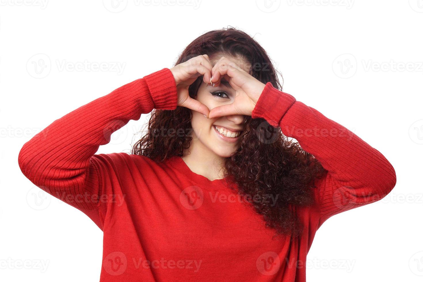 girl peeking through heart shape hand sign photo