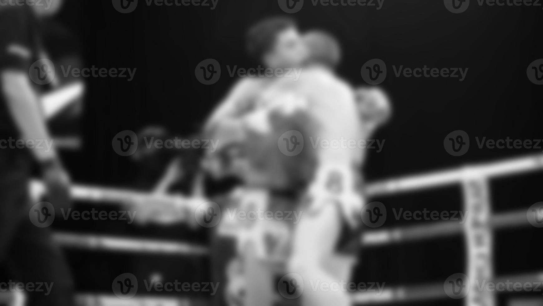 Blurred images black and white photo style of Thai boxing or Muay Thai or Kickboxing which local and foriegn boxer are fighting on the ring at indoor stage as martial art sport. Muay Thai Kick boxing