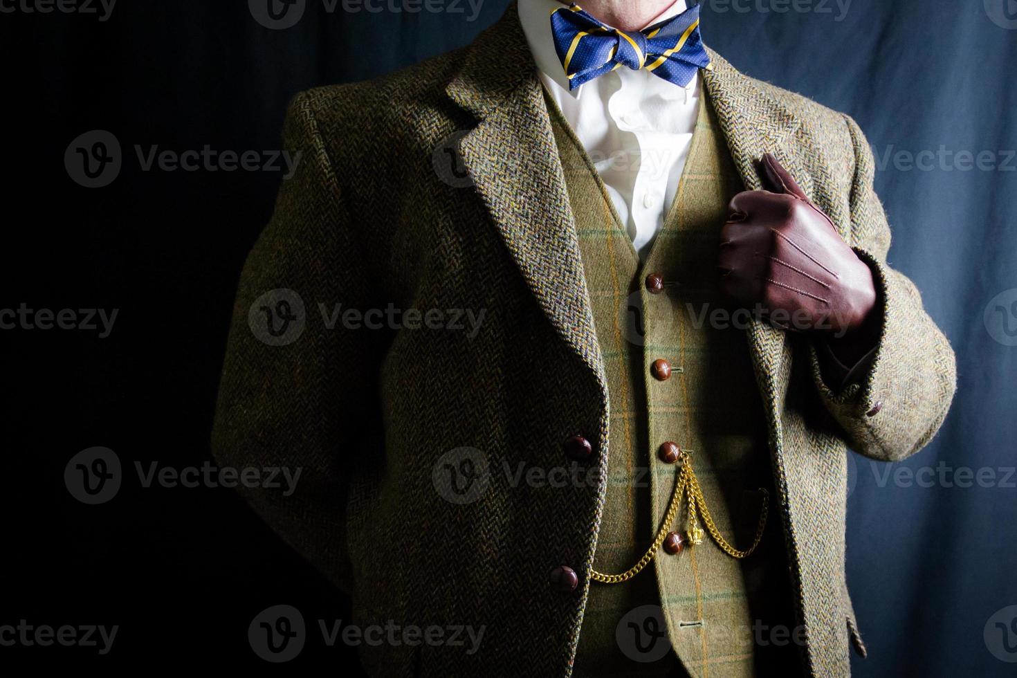 Portrait of Man in Tweed Suit and Leather Gloves Standing Proudly on Black Background. Classic and Eccentric English Gentleman. Retro Style and Vintage Fashion. photo