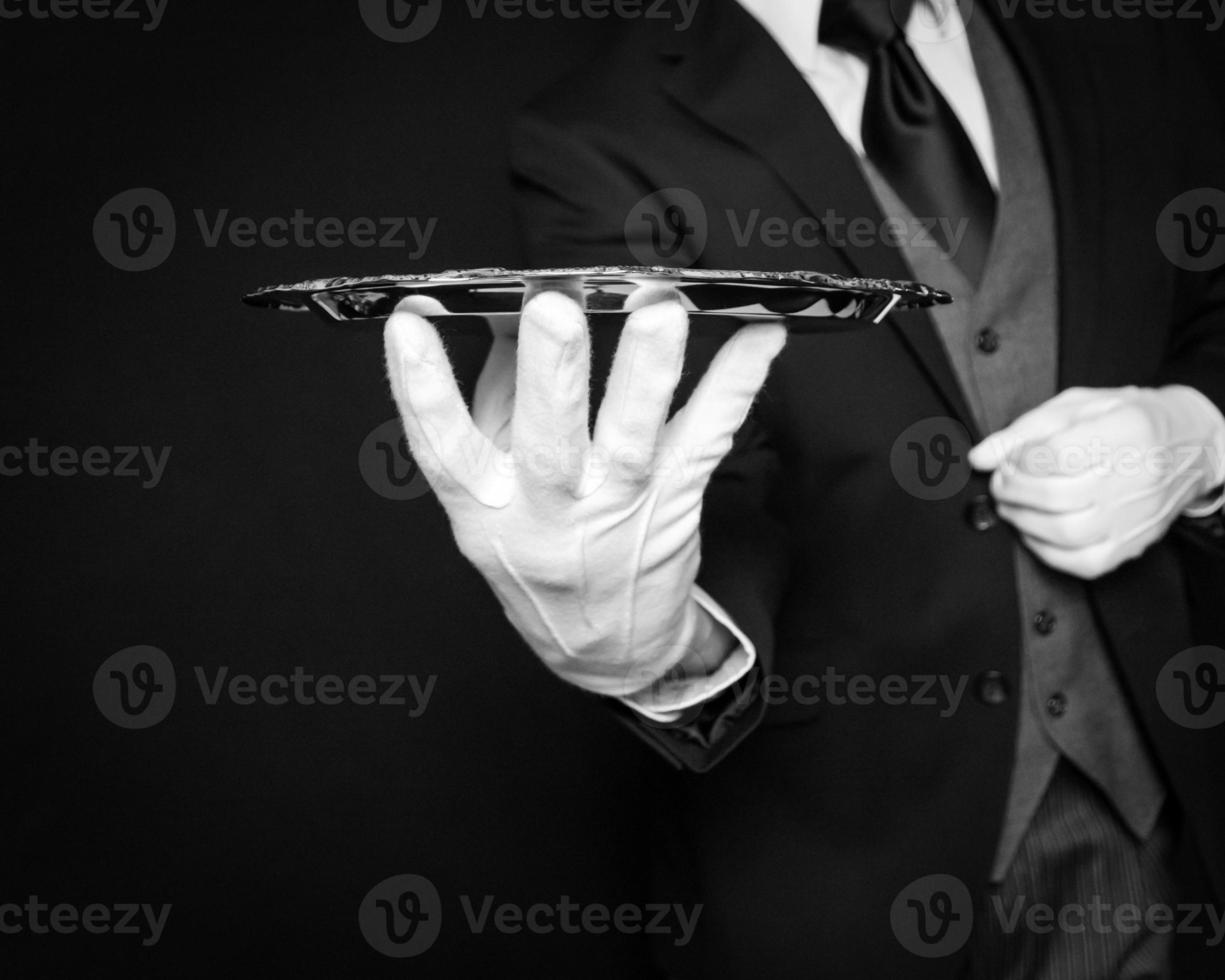 Close Up of Butler or Waiter in Dark Suit and White Gloves Holding Silver Serving Tray on Black Background. Elegant and Professional Service. photo