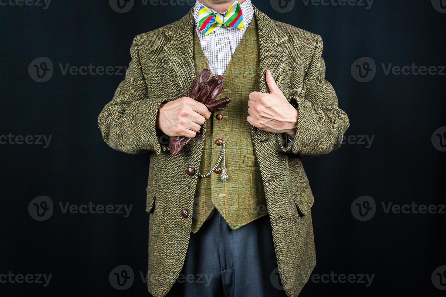 Portrait of Successful Man in Tweed Suit Holding Pair of Brown Leather Gloves. Concept of Classic British Gentleman Stereotype photo