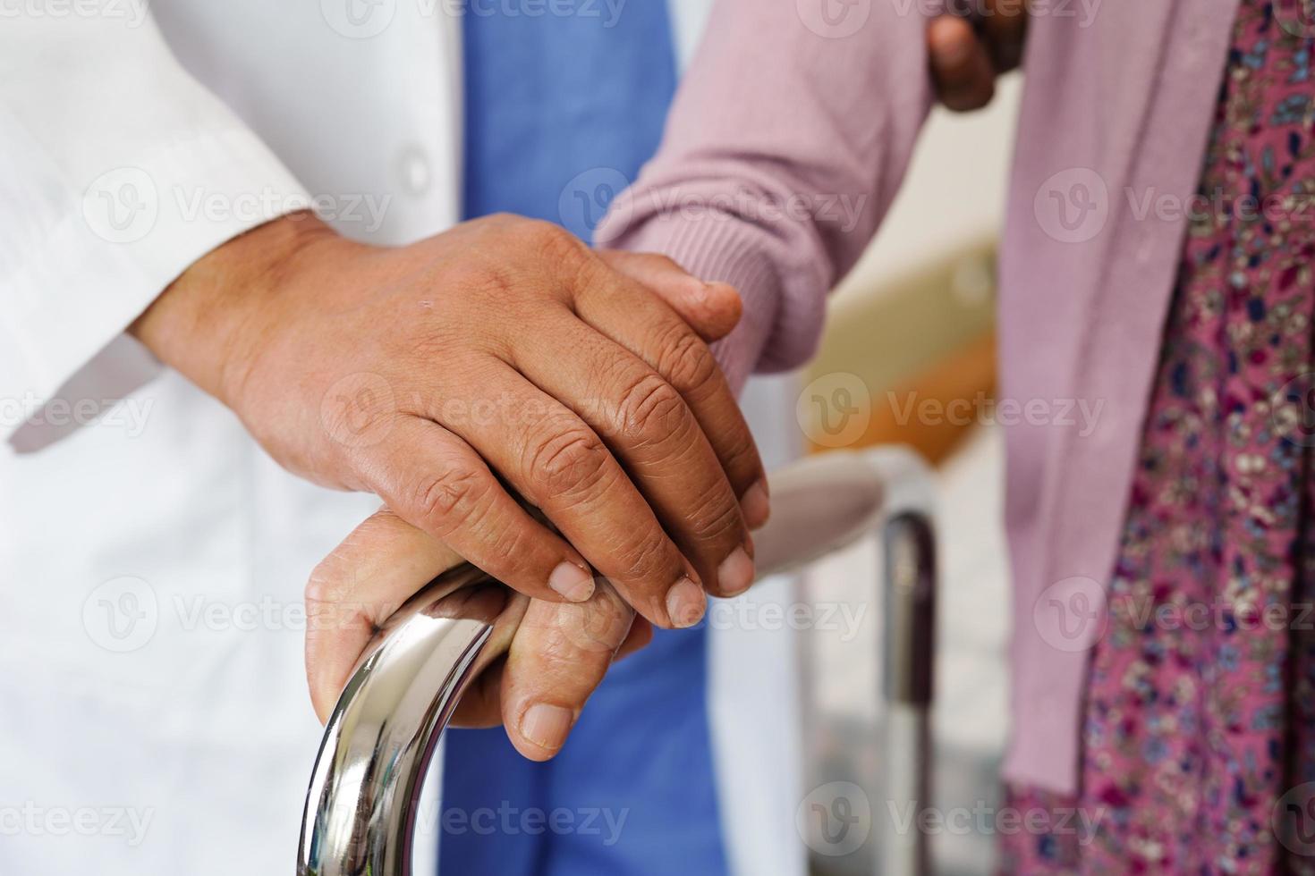 Doctor help Asian elderly woman disability patient walk with walker in nursing hospital, medical concept. photo