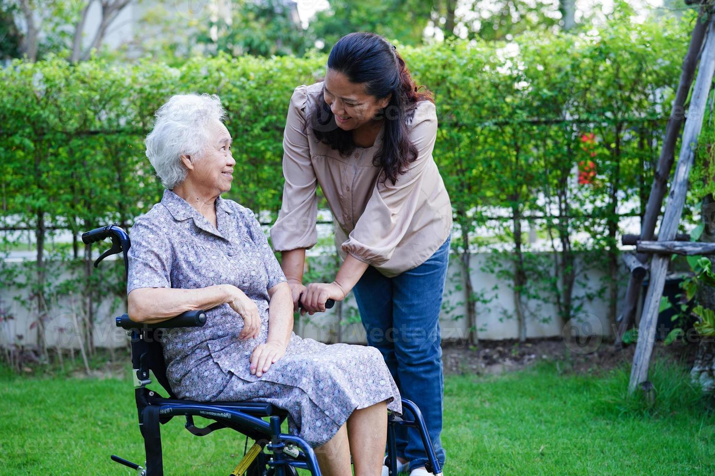 Caregiver help Asian elderly woman disability patient in nursing hospital, medical concept. photo