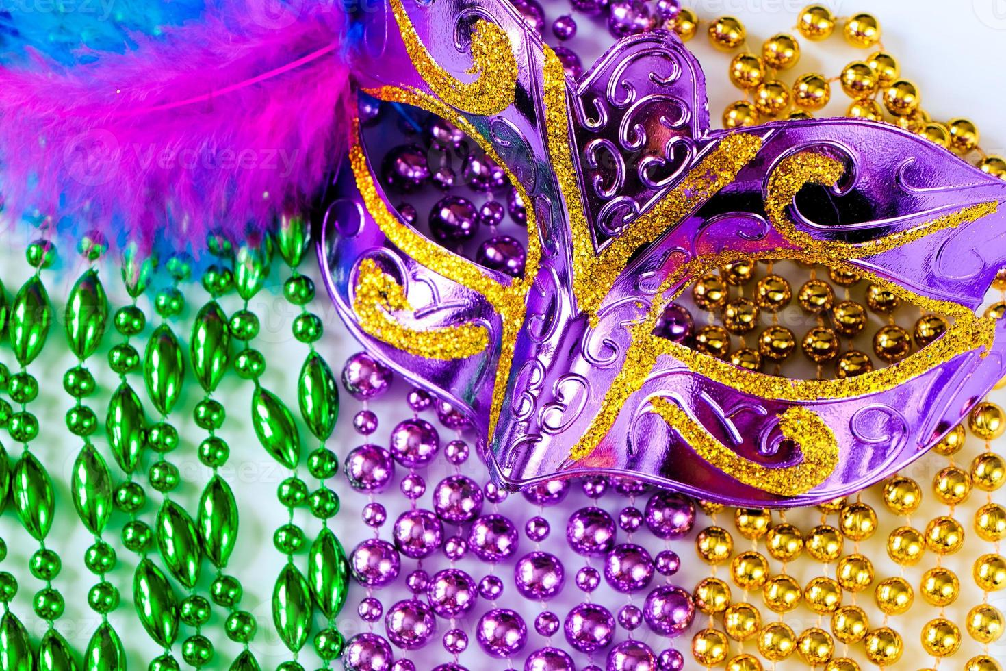 Purple carnival mask with feathers and colorful beads close-up. Mardi Gras or Fat Tuesday symbol. photo