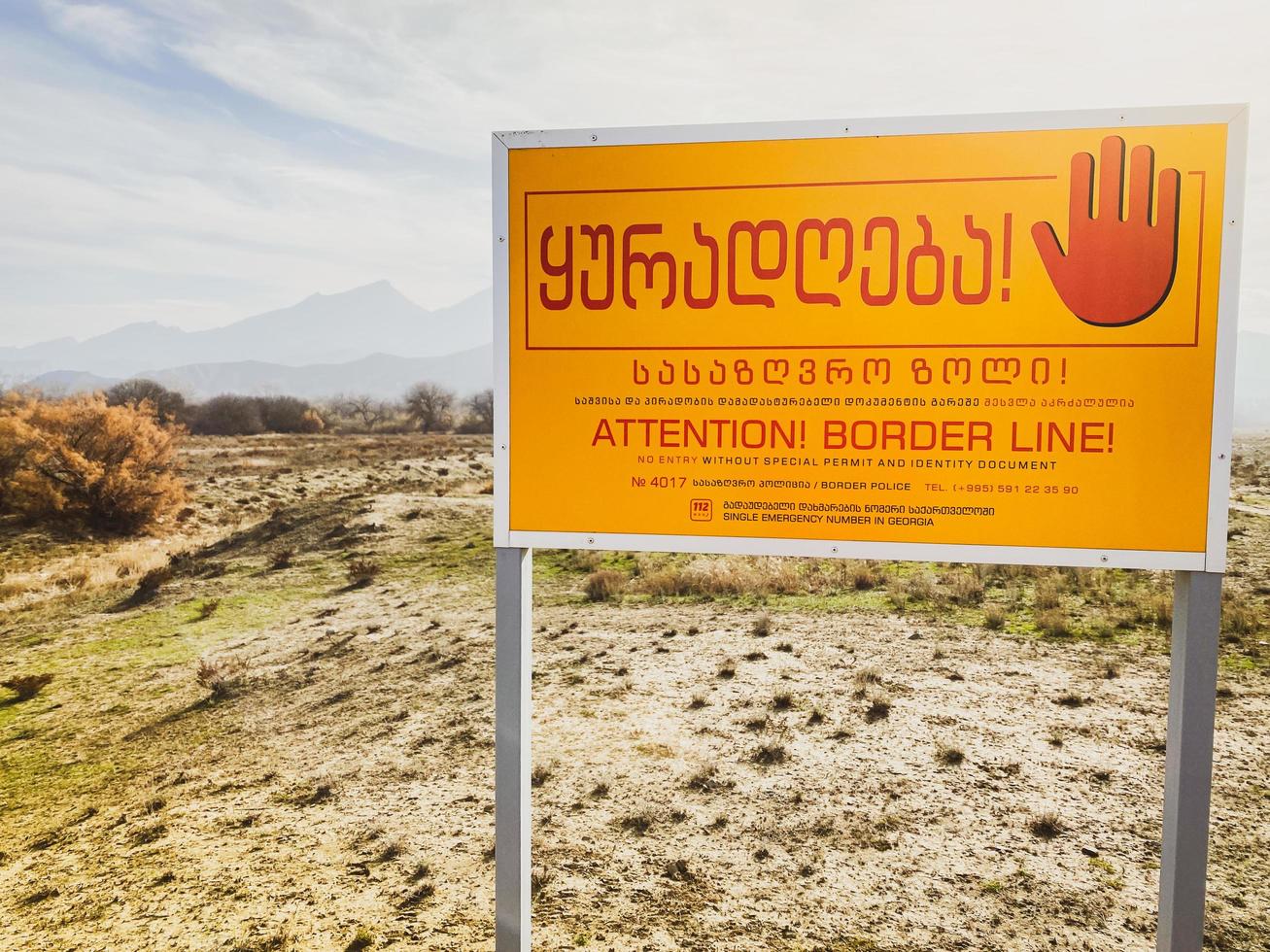 cartel de advertencia sobre la zona fronteriza entre azerbaiyán y georgia. río cruzando la línea fronteriza de las montañas. foto