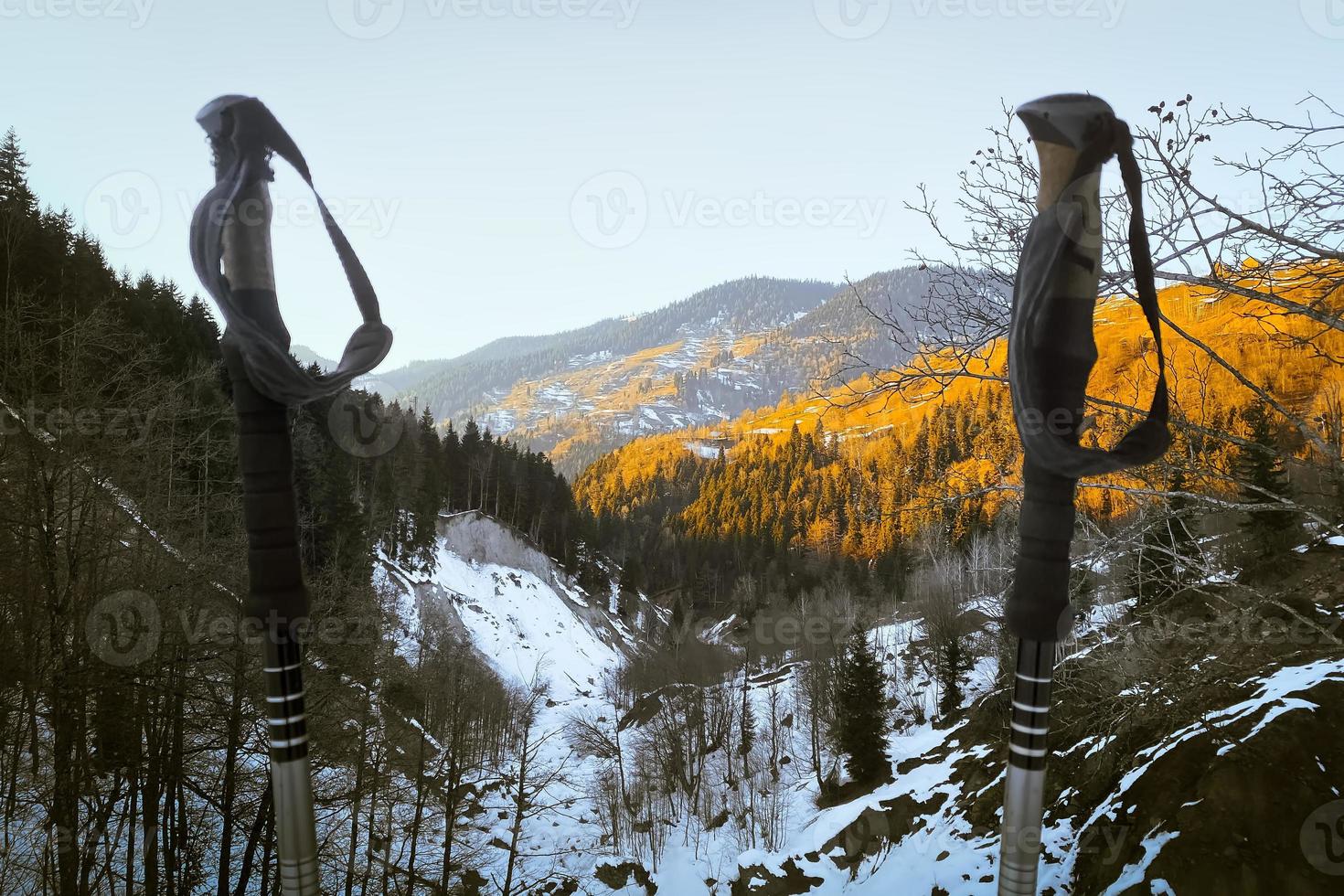 Close up black grey hiking poles on hike with mountains panorama in spring photo