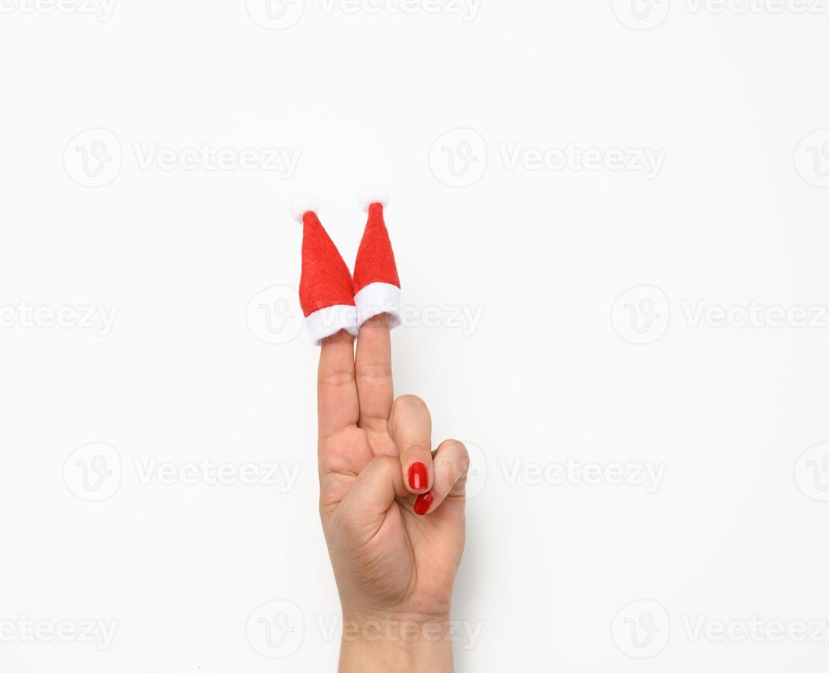 female hand with handsome red christmas caps on fingers, white background photo