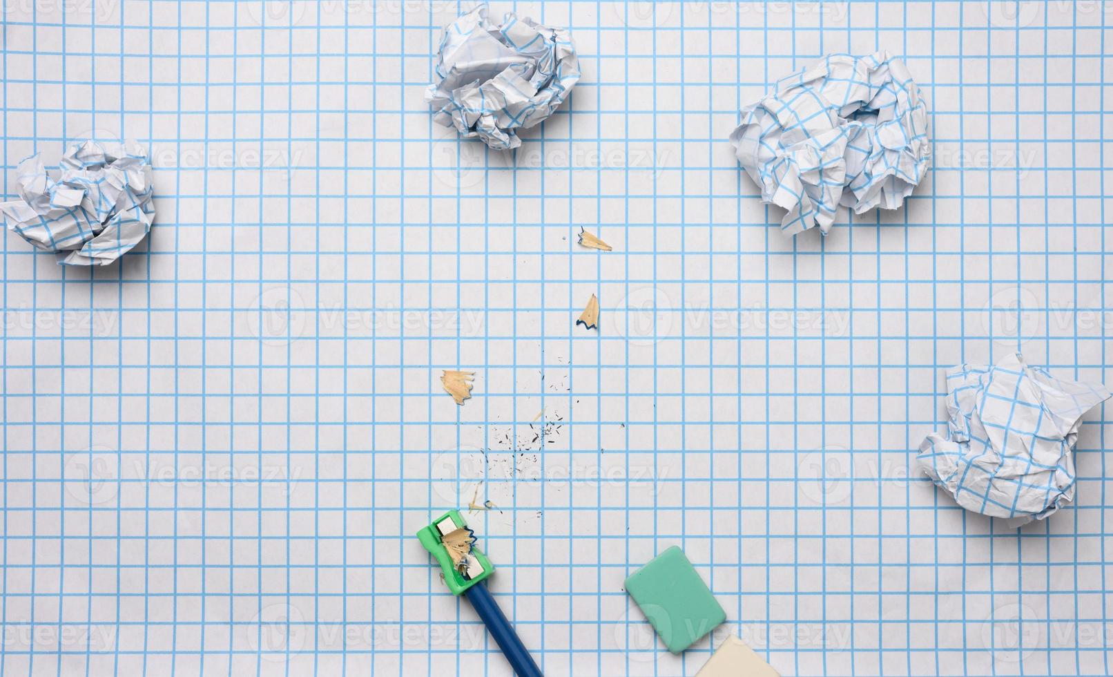 crumpled paper balls and a sharpened wooden pencil with shavings on a checkered paper sheet photo
