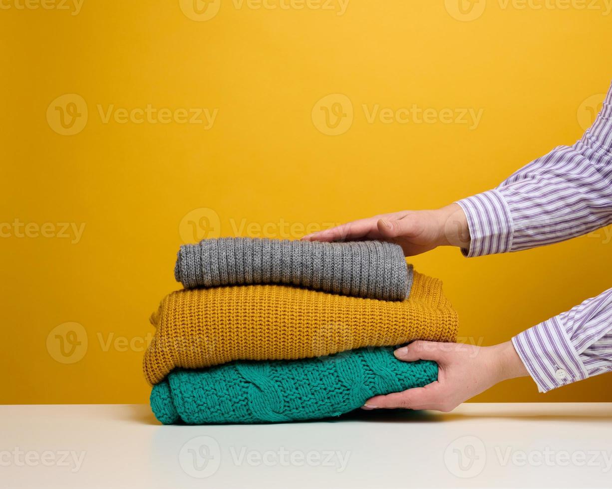 a woman holds a stack of washed folded things on a yellow background. Home routine work photo