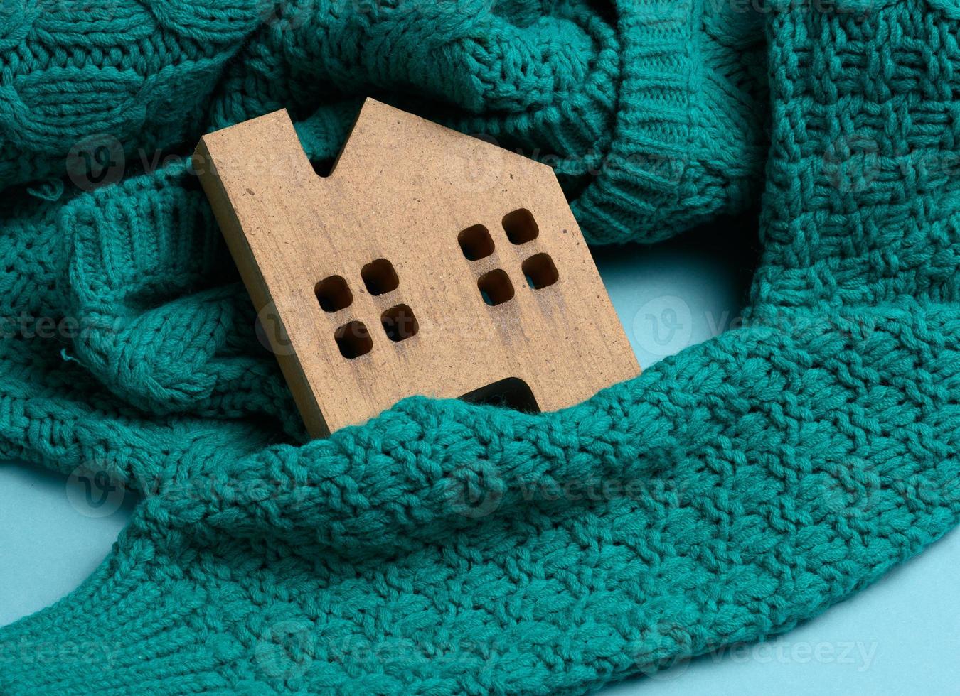 el modelo de madera marrón de la casa está envuelto en un cálido suéter de punto. concepto de préstamo para aislamiento de casas, energía alternativa foto